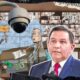 Cruz Pérez Cuéllar frente a un centro de monitoreo en Ciudad Juárez, observando una cámara de vigilancia, con caricatura de corrupción en la escena